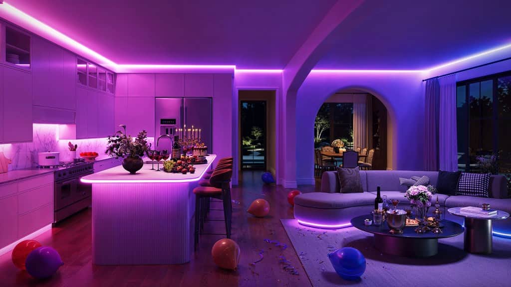 Modern kitchen and living room with purple LED lighting, featuring a central island with fruit, wine glasses, and candles, surrounded by colorful balloons and a stylish sofa.