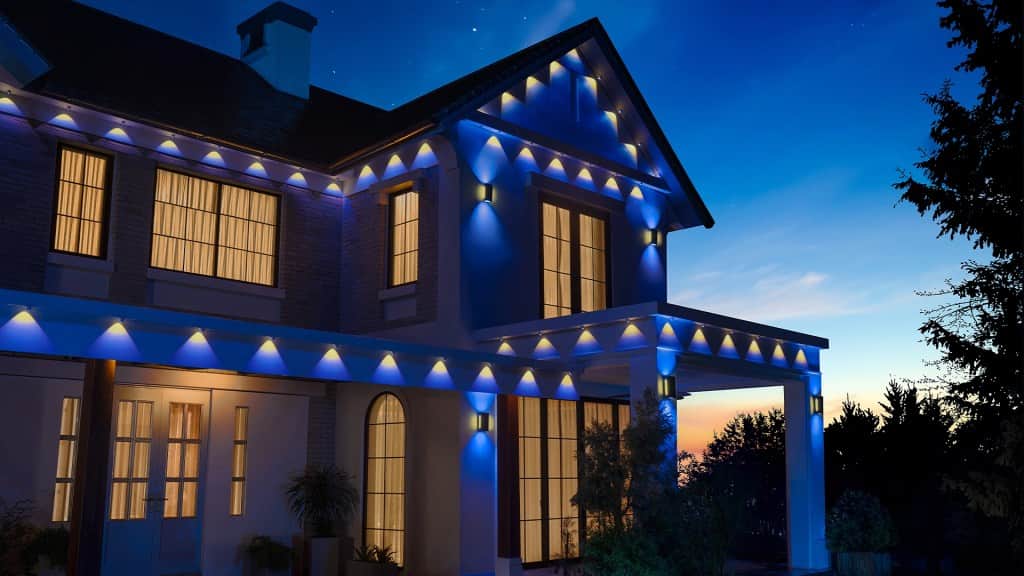 A modern house illuminated with blue lights at dusk, featuring large windows and a welcoming porch.
