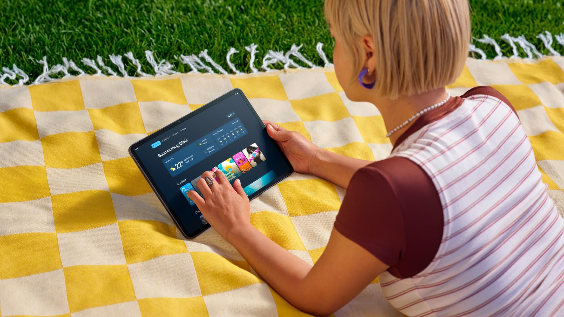 A girl using the Amazon Alexa Tablet 12 Pro on a picnic blanket — The Alexa Tablet 12 Pro can be configured with an anti-glare Nanomatte display. Image credit: Amazon
